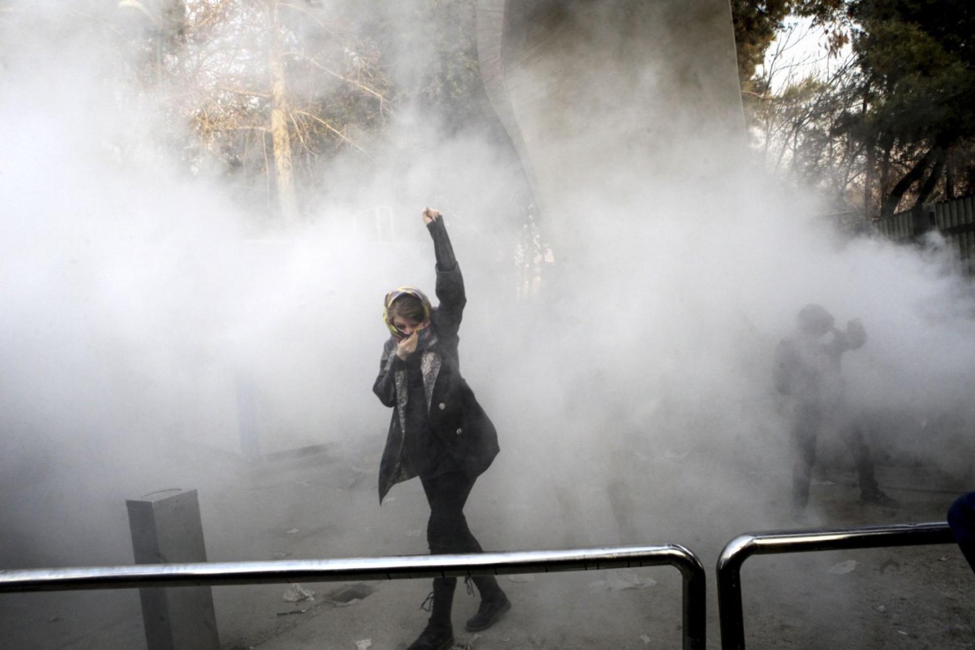 Eine Frau bei einem Protest mit Nebel. Sie hebt die Faust.