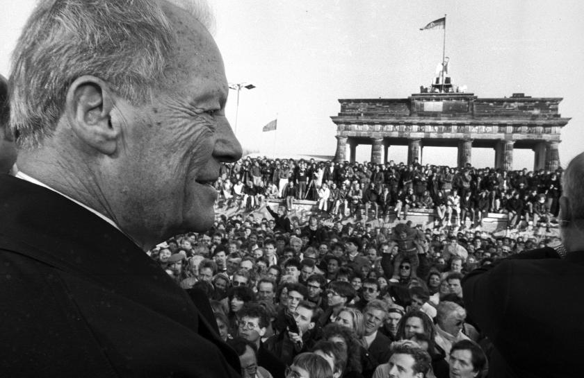 Ein Foto von Willy Brandt vor einer Menschenmenge am Brandenburger Tor.