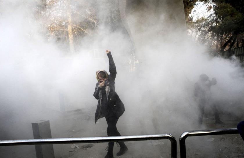 Eine Frau bei einem Protest mit Nebel. Sie hebt die Faust.