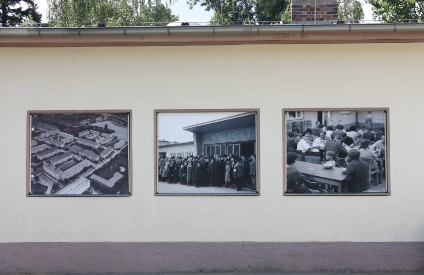 Eien Außenwand des Notaufnahmelagers Marienfelde mit historischen Fotos von Flucht.